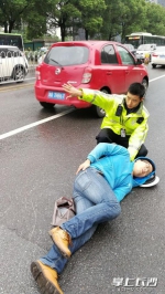 看受伤的电动车司机躺在地上无法动弹，肖亮摘下警帽垫在他头下，一边疏导交通。交警供图 - 新浪湖南